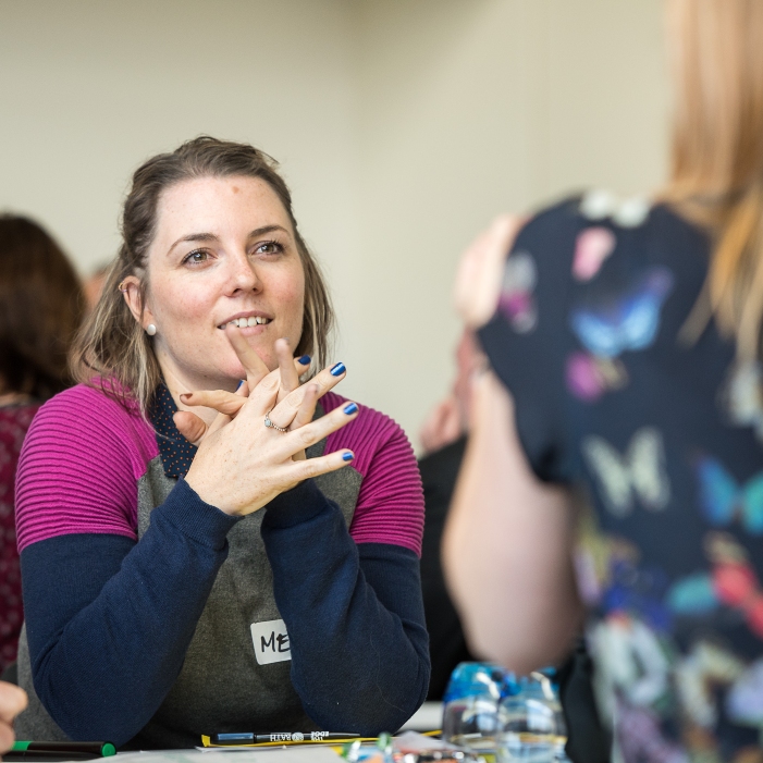 A woman looks inspired as she listens to someone talking opposite her