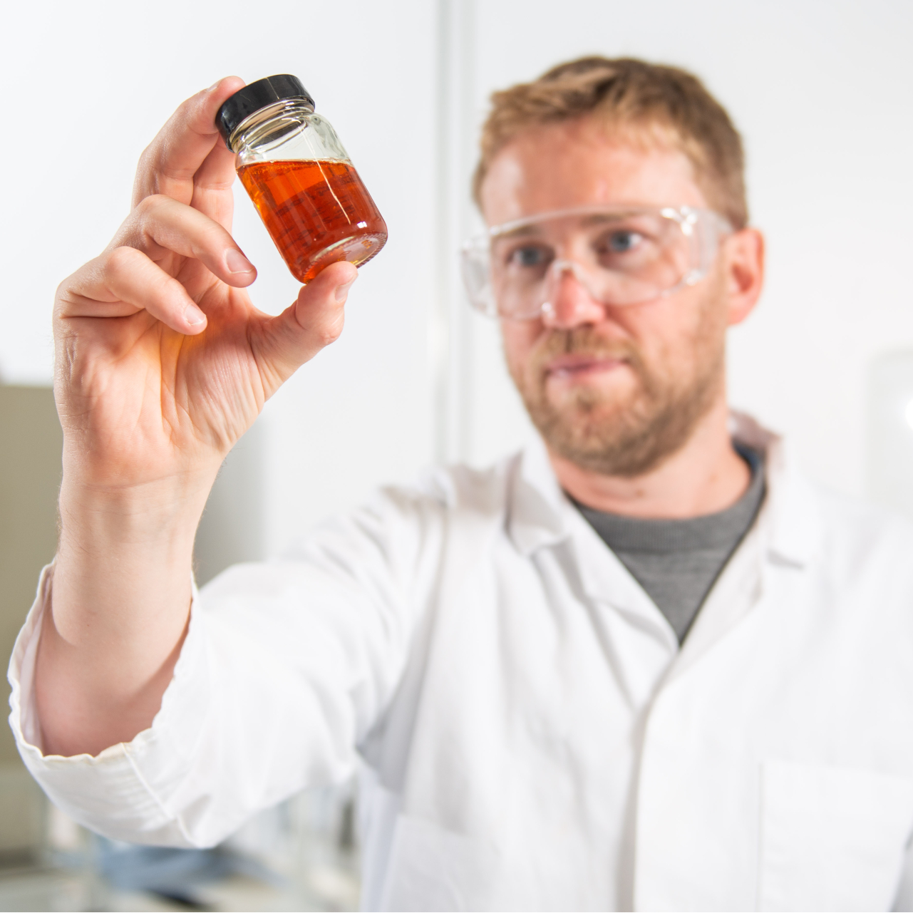 A researcher holding a bottle of oil