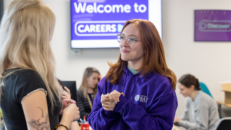 A student receiving support from a Student Employability Coach in a purple hoodie